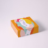 A colorful box with abstract shapes and a logo on top, featuring shades of yellow, orange, pink, and green.