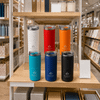 A drink bottle display featuring six Siena Vacuum Tumblers in white, red, orange, blue, black, and teal, with branding.