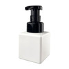 A square white foaming soap dispenser with a black pump top. Features a logo on the front.