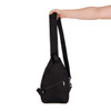 A black shoulder bag with a single strap, featuring a zippered pocket and a hand holding it.