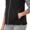 A black women's softshell vest featuring a zip front and side pockets, with grey sleeves and a branding logo.