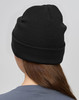 A black beanie made from rPET, displayed from the back on a model with long hair. It features a logo.