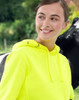 A bright yellow water-resistant fleece hoodie with a hood, featuring a logo, shown against a natural background.
