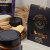 A black packaging of Savoury Nut Mix displayed with various gourmet snacks, including cheese and biscuits.