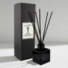 A square black reed diffuser with black reeds, packaged in a matching box, featuring a minimalist design.