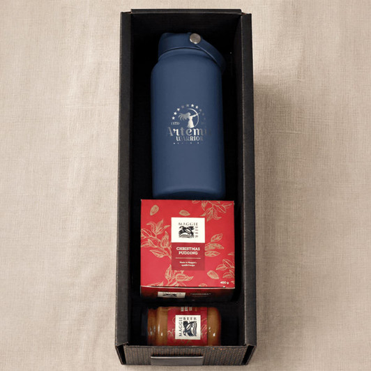 A blue drink bottle, a Christmas pudding, and a jar of sauce in a black box hamper.
