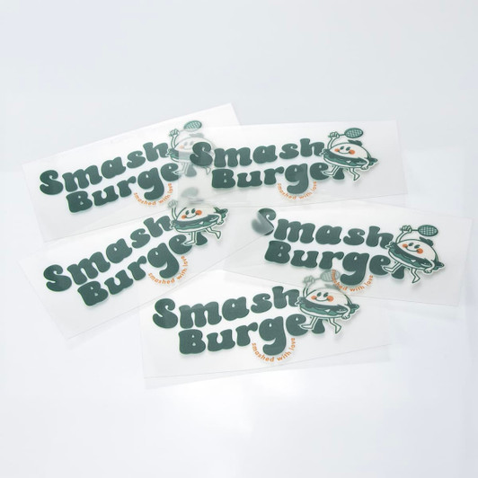 A collection of green and white stickers featuring a playful logo and branding for "Smash Burger."