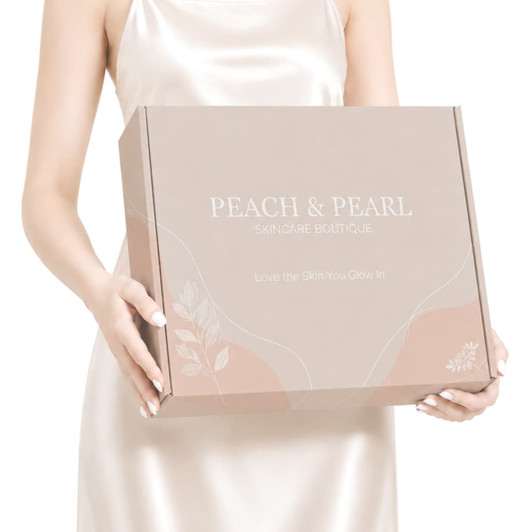 A light beige box with a locking lid, featuring floral motifs and a logo, held by a person in a satin dress.