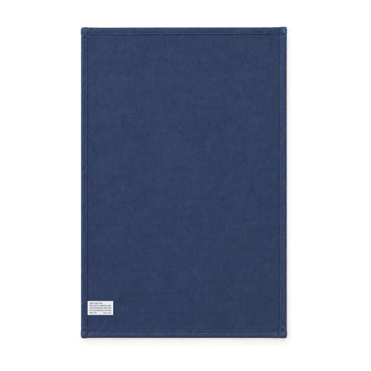 A medium cotton tea towel in navy blue with stitched edges and a small tag. It has a simple design and a logo.