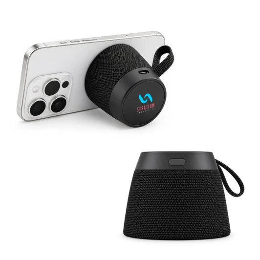 A black portable speaker with a fabric design, displayed with a phone leaning against it. Features a logo.