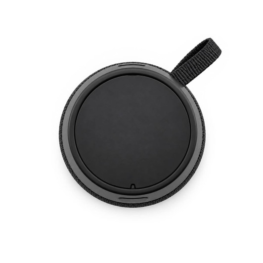 A round black speaker with a textured fabric edge and a loop for attachment. It has a smooth, flat surface on top.