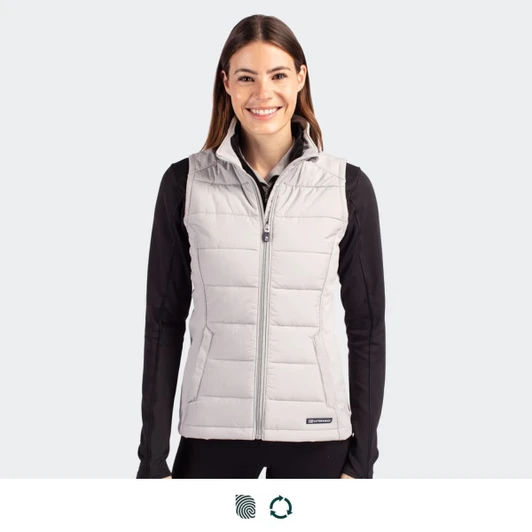 A woman is wearing a light grey, sleeveless hybrid vest with a zip front, featuring a branding logo.