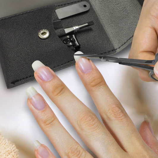 A black manicure set with scissors and tools, featuring a hand with well-groomed nails using the scissors.