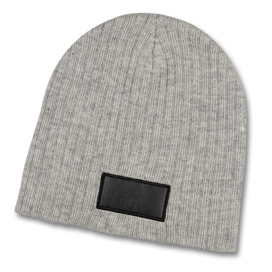 A grey cable knit beanie with a patch on the front, featuring ribbed texture and a rounded top.