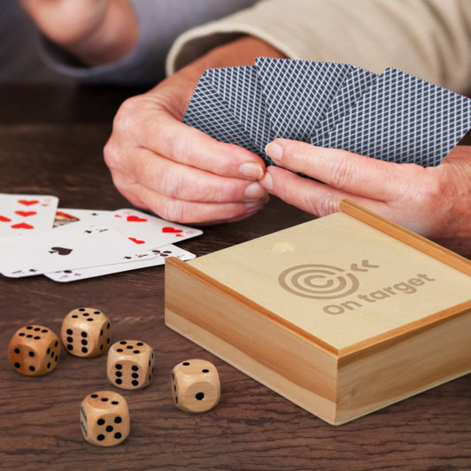 A wooden card game set with a box, playing cards, and wooden dice on a table, featuring grey and natural tones.