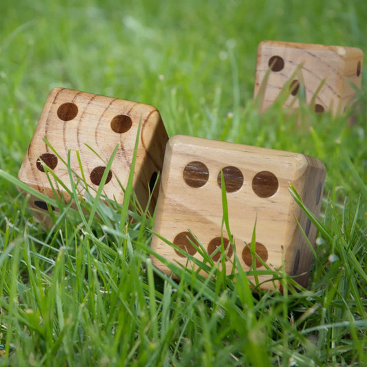 A set of wooden yard dice in natural wood colour, resting on green grass.