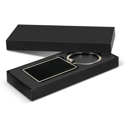 A rectangular black key ring with a metallic finish, presented in a sleek black box.