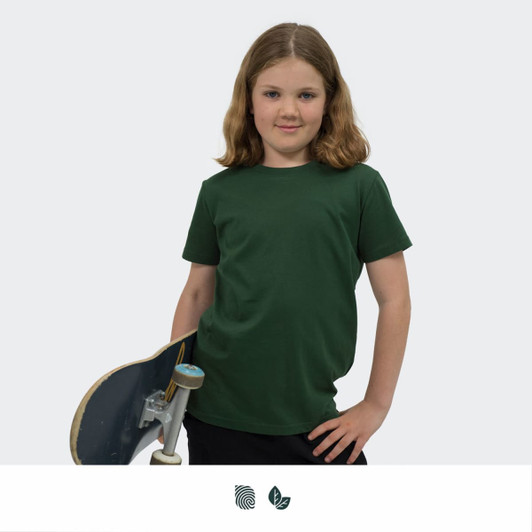 A youth t-shirt in dark green, displayed by a child holding a skateboard, featuring a logo.