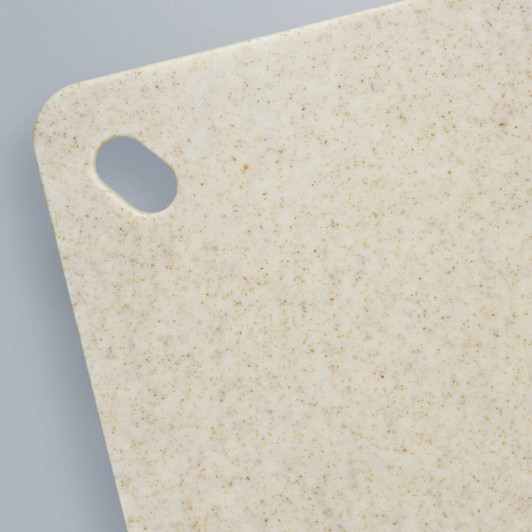 A chopping board in a speckled beige colour, featuring a corner cut-out for hanging.