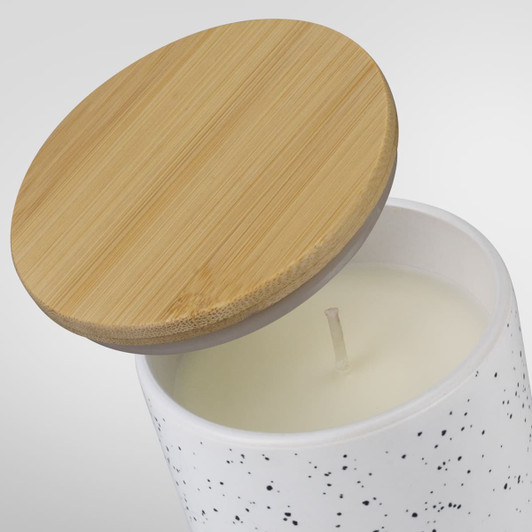 A white candle with a speckled design and a bamboo lid, showcasing its clean and modern aesthetic.