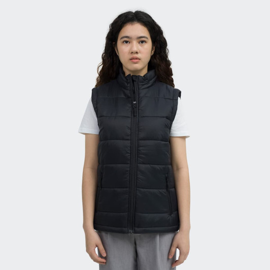 A woman models a black puffer vest with a front zip and a high collar, featuring a logo.