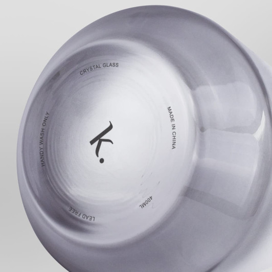 A crystal whiskey glass featuring a smooth finish, with a logo and text on the base. The glass is transparent.