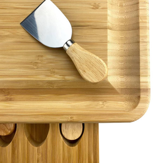 A bamboo cheeseboard with a stainless steel knife and rounded edges, featuring cut-outs for additional utensils.
