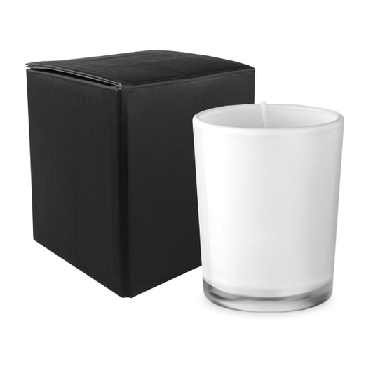 A glass candle in a clear container next to a black box. The candle is white and has a simple design.
