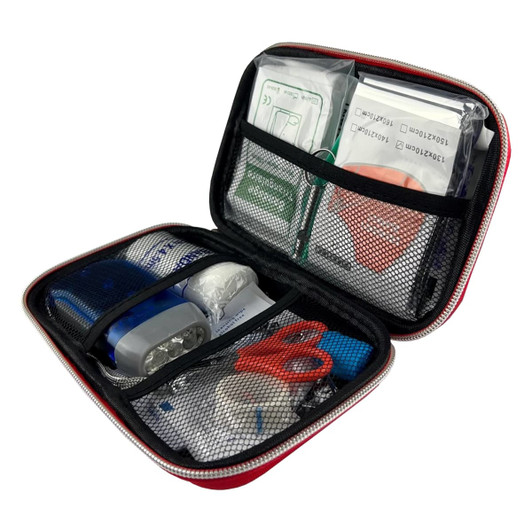 A red first aid case contains various medical supplies, including adhesive bandages, scissors, and antiseptic wipes, in mesh pouches.