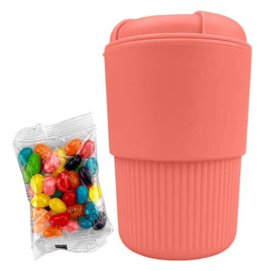 A reusable coffee cup in coral with a ribbed design, accompanied by a bag of colourful jelly beans.