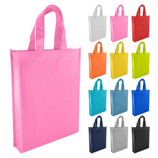 A pink non-woven tote bag with two handles, surrounded by bags in various colours including red, blue, yellow, and green.