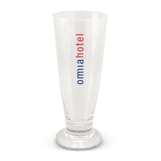 A clear beer glass with a tall, slender design and a base, featuring a logo in red and blue.