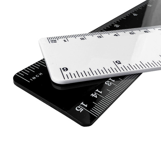 A plastic ruler featuring white and black colours, with metric and imperial measurements, and a logo on its surface.