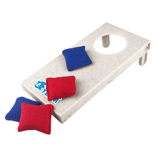 A Wheat Straw Cornhole board in light beige with a hole, accompanied by red and blue bean bags.