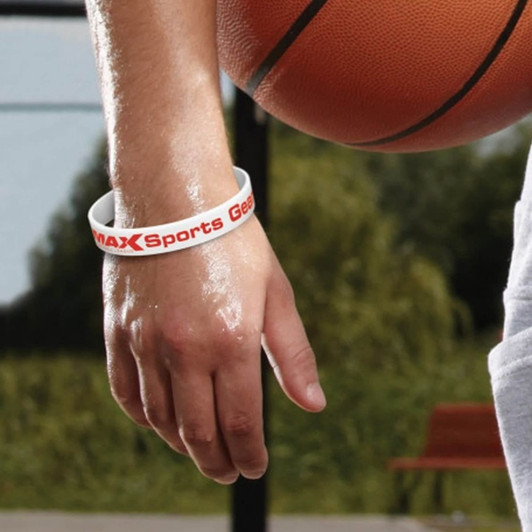 A silicone wristband in white with red branding is worn on a hand next to a basketball.
