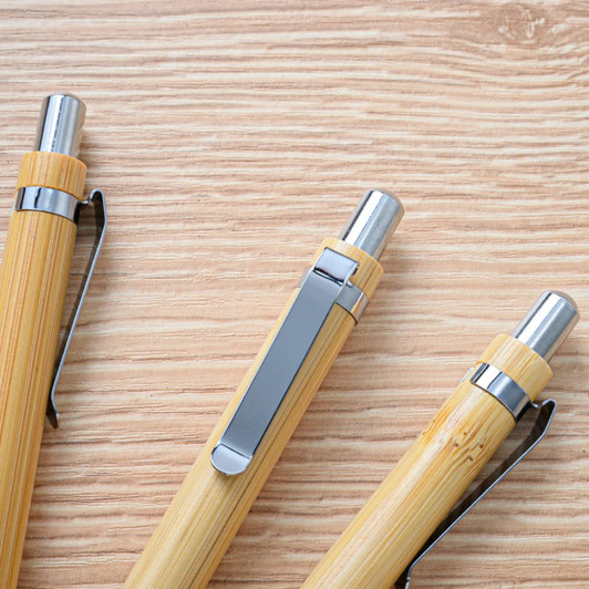 A set of bamboo pens with metallic tips and clips, arranged on a wooden surface.
