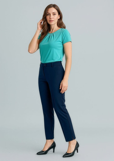 A woman stands wearing a turquoise top and navy slim leg pants, paired with black high heels. The image features a branding logo.