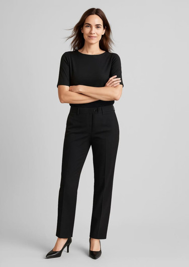 A woman wears black comfort wool stretch relaxed pants paired with a black top and high heels, standing confidently.
