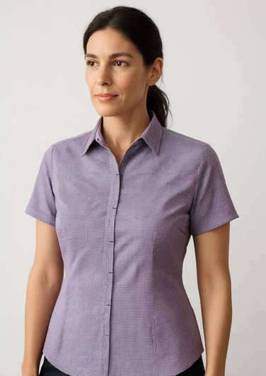 A short sleeve shirt in a purple check pattern with a button-up front and a collar. It has a logo on it.