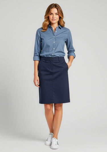 A woman in a blue shirt and navy Lawson skirt, standing confidently with one hand on her hip.
