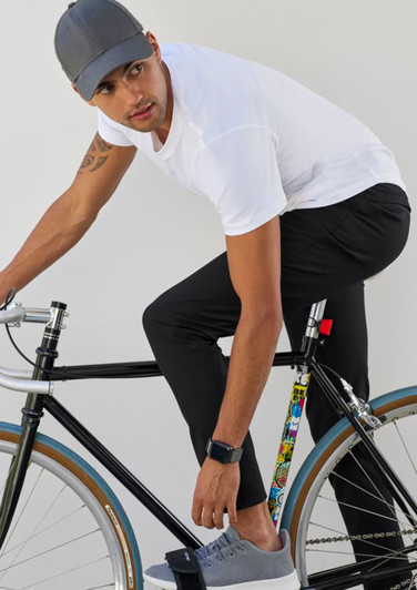 Mens Venture Pant in black, worn by a man on a bicycle, styled with a white t-shirt and grey shoes. Features a logo.