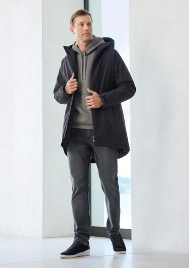 A unisex black rain jacket over a grey hoodie, paired with grey pants and black sneakers. The jacket features a hood.