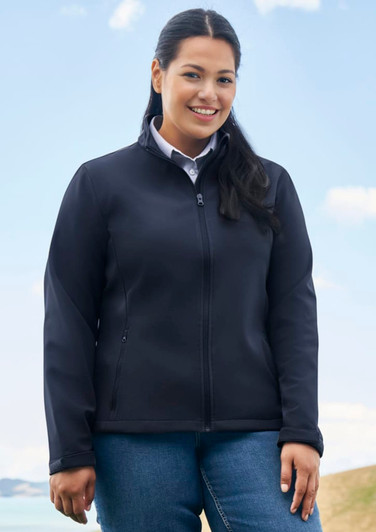 A black soft shell jacket with a zip front, worn by a woman outdoors against a scenic backdrop.