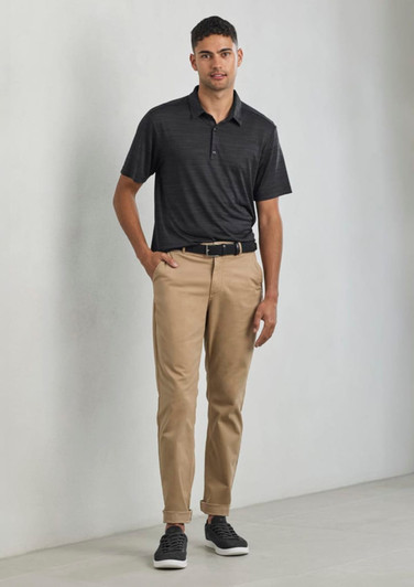 A black short sleeve polo shirt with a subtle pattern, paired with beige trousers and sneakers. The model stands confidently.