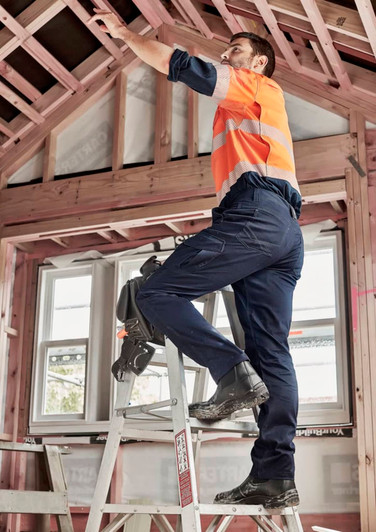 A man in orange and grey high-visibility workwear wears navy cargo pants while standing on a ladder.
