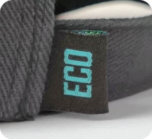 A close-up of a black cap's label featuring the word "ECO" in light blue text. The cap has a textured fabric.