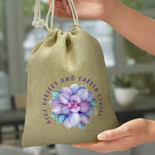 A medium jute gift bag in a natural tone, featuring a floral design and a logo.