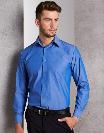 A blue long sleeve button-up shirt with a chest pocket and a logo, worn by a man against a grey background.