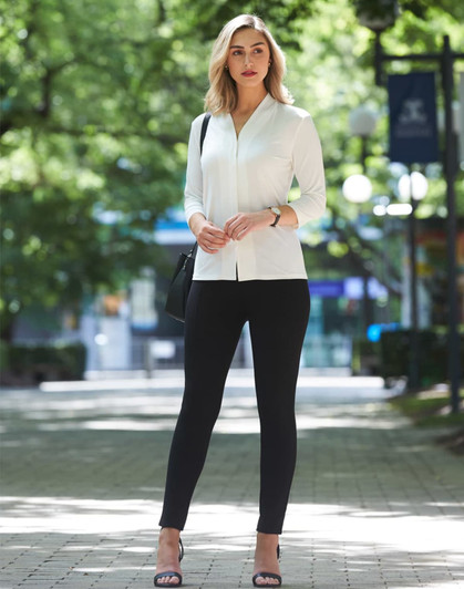 A mid sleeve knit top in white, paired with black leggings, set against a green park backdrop. The model carries a bag.
