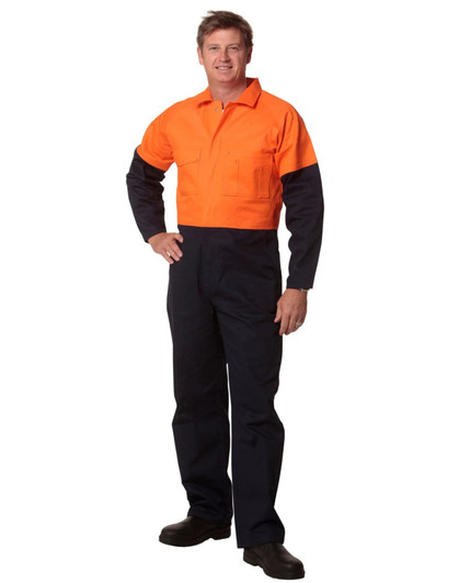 A man stands wearing a two-tone high-visibility cotton drill coverall in orange and navy blue. The coverall features pockets and has a logo.